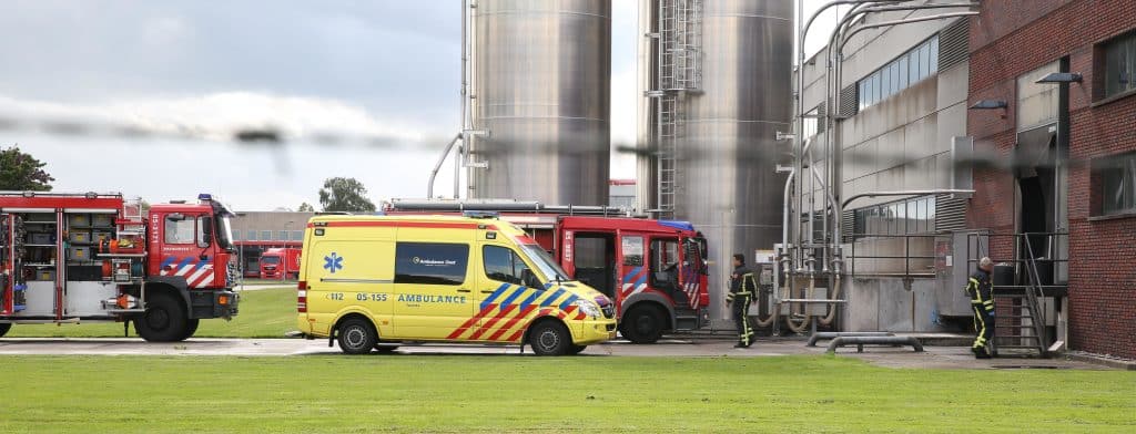 Ambulances en brandweerauto's buiten een fabriek